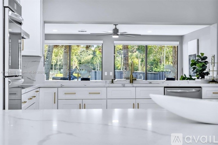 A modern kitchen with white cabinets and a marble countertop.