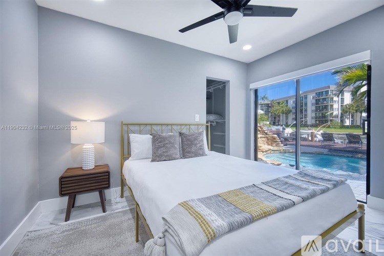 A bedroom with a large bed and a view of the pool outside.