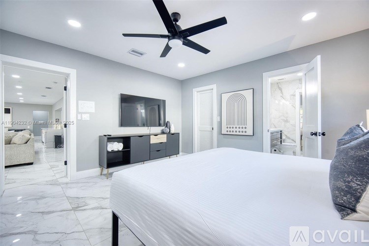 A bedroom with a large bed, a ceiling fan, and a television.