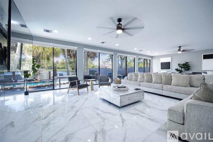 A spacious living room with a marble floor and a ceiling fan.