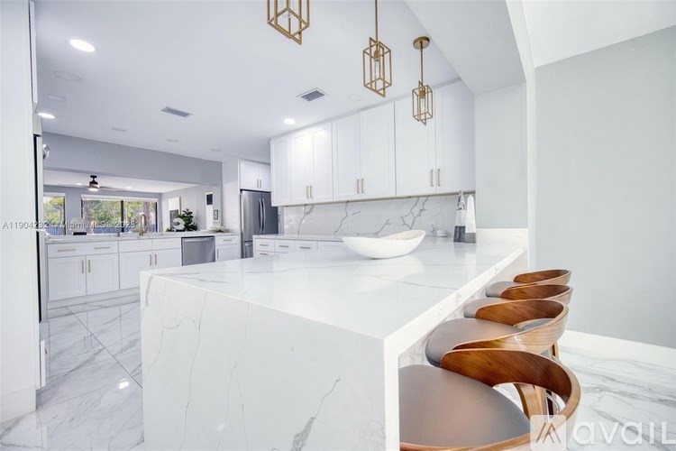 A modern kitchen with a marble island and wooden chairs.