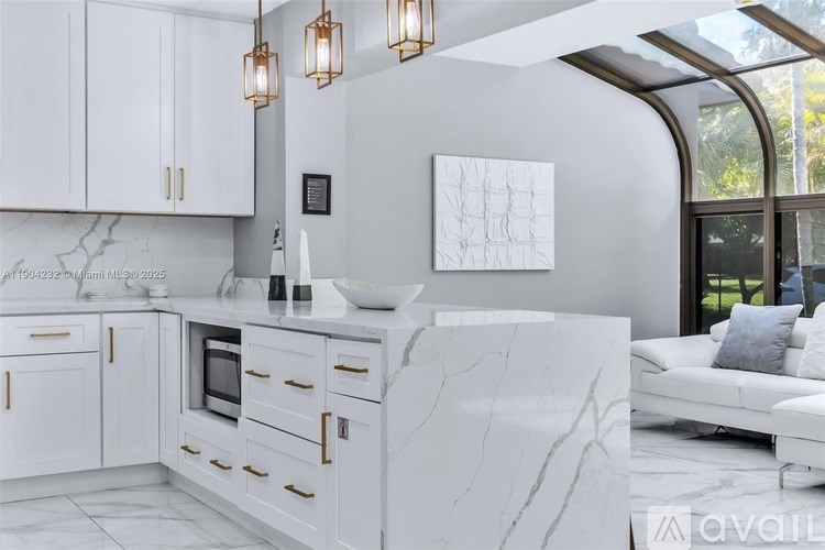 A modern kitchen with white cabinets and marble countertops.