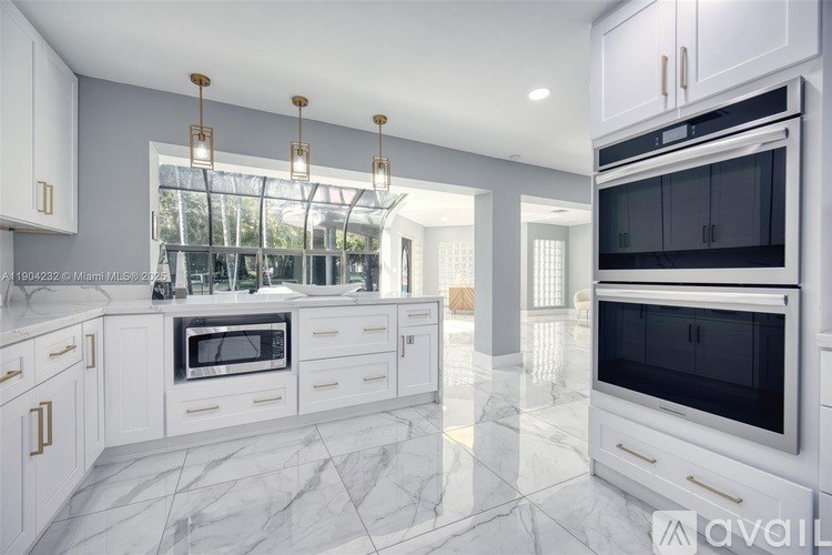 A modern kitchen with white cabinets and marble flooring.
