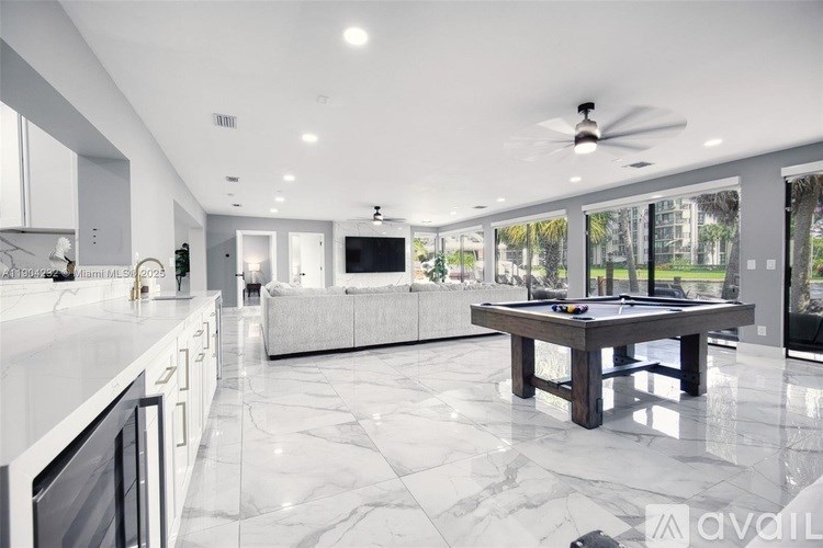 A modern kitchen with a marble floor and a pool table.