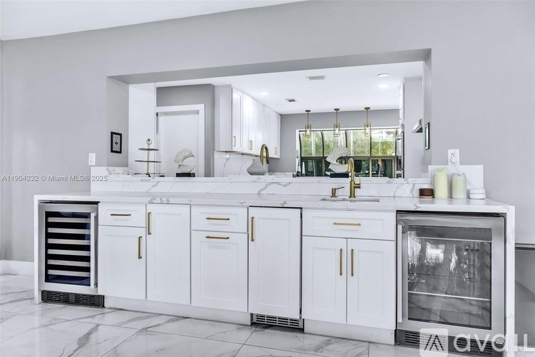 A modern kitchen with white cabinets and a marble countertop.