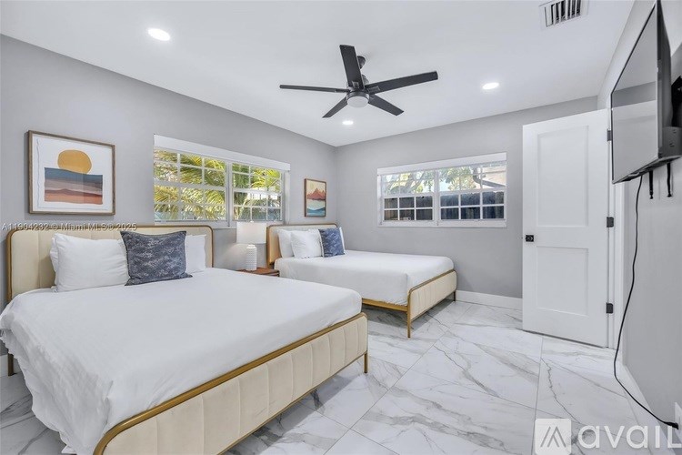 A bedroom with two beds and a ceiling fan.