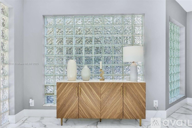 A wooden cabinet with a glass block wall behind it.