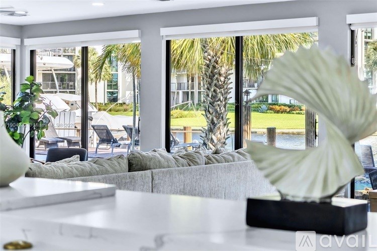 A modern living room with a view of a palm tree through the window.