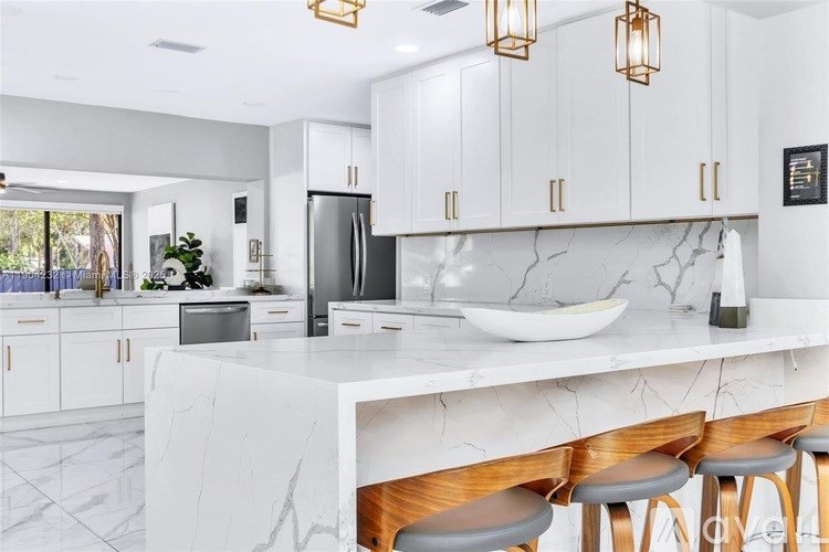 A kitchen with white cabinets and a marble countertop.
