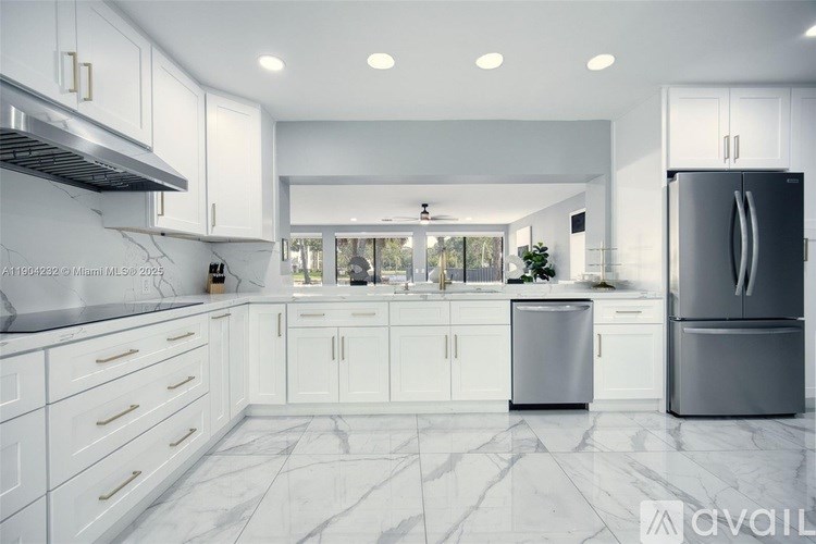 A modern kitchen with white cabinets and marble flooring.