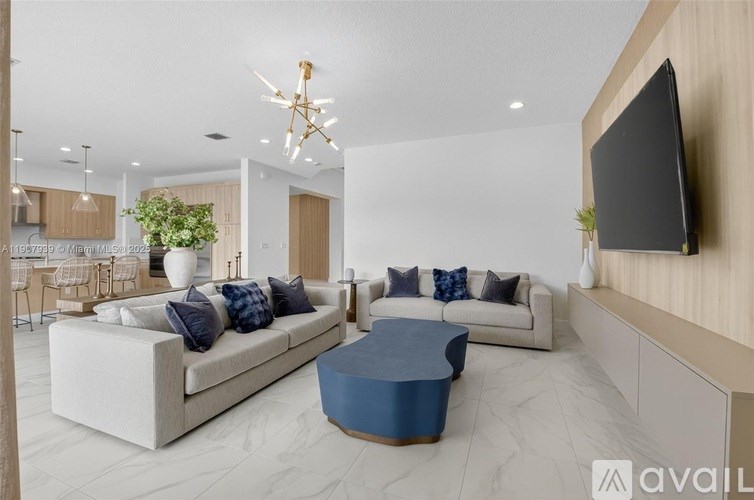 A modern living room with a large sofa and a television on the wall.