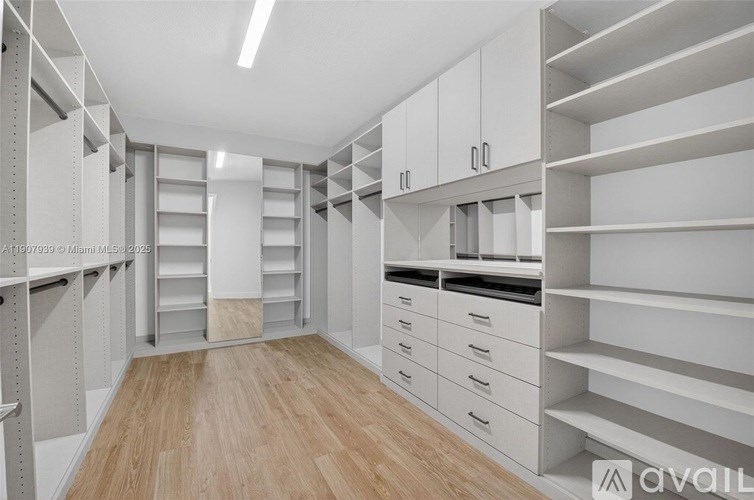 A spacious walk-in closet with white shelving and drawers.