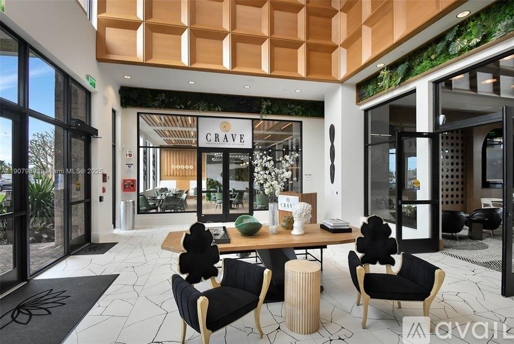A modern interior with a wooden table and chairs, a sign that reads "CRAVE", and a green wall with plants.