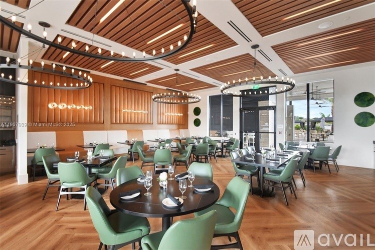 A modern restaurant with wooden floors and green chairs.