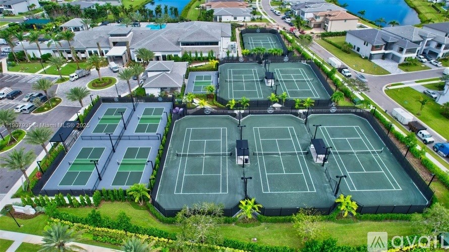 A tennis court surrounded by greenery and residential buildings.