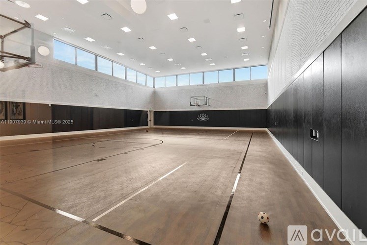 A large indoor court with a wooden floor and a ball on it.
