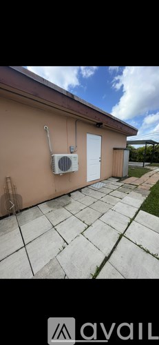 A tan building with a white door and a window with an air conditioner unit outside.