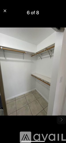A small, empty room with a tiled floor and a wall-mounted coat rack.