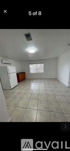 A spacious room with tiled flooring and a window with blinds.
