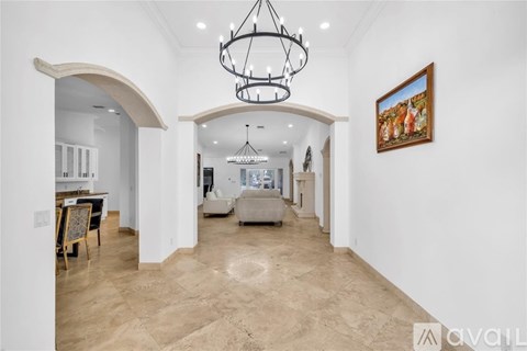 A spacious living room with a chandelier and a painting on the wall.