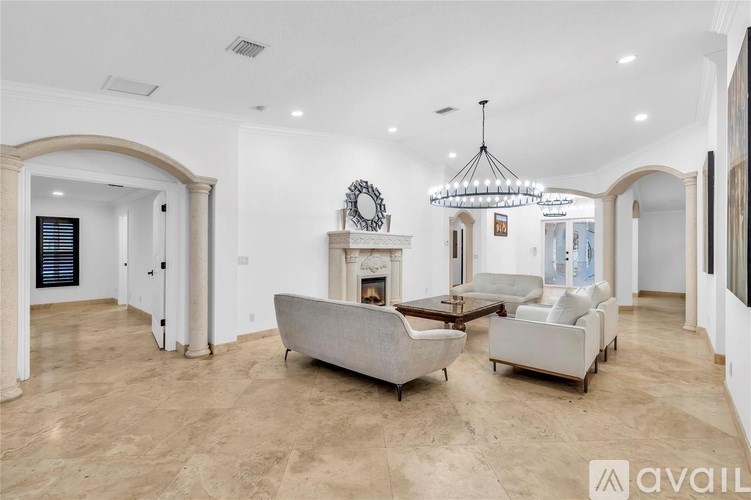 A spacious living room with a fireplace and a chandelier.