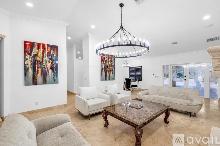 A living room with a large painting on the wall and a chandelier hanging from the ceiling.
