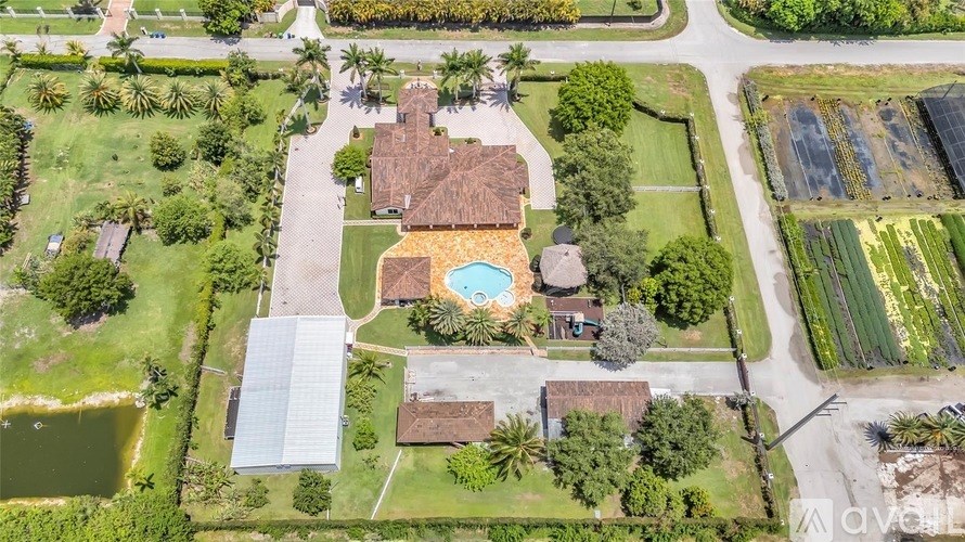 A bird's eye view of a residential area with a house, a swimming pool, and a green lawn.