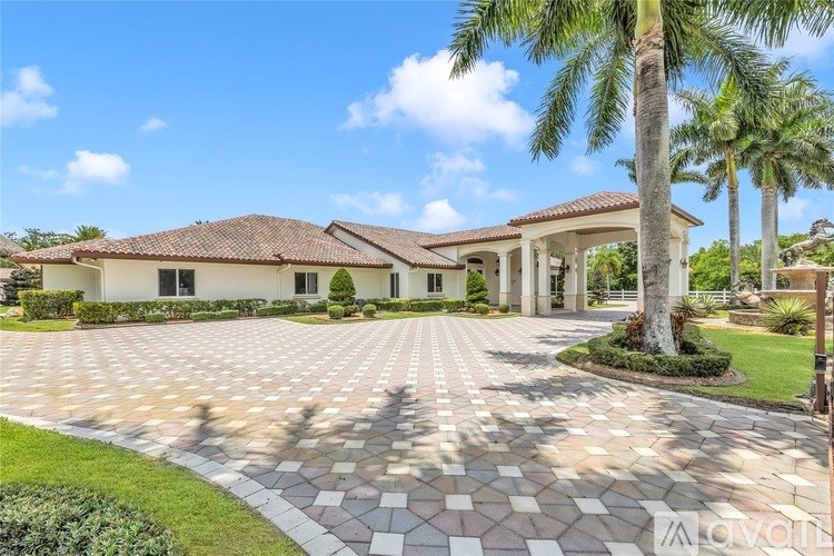 A large house with a tiled driveway and a palm tree in front.