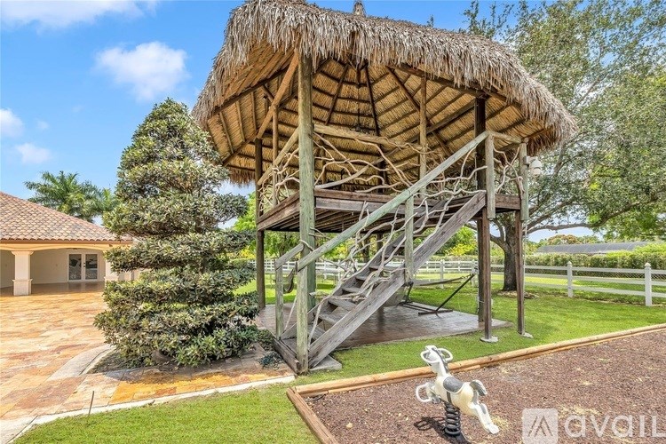 A wooden structure with a thatched roof and stairs leading up to it.