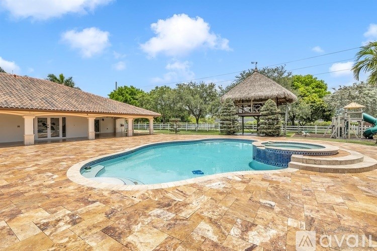A large outdoor swimming pool surrounded by a tiled patio area.