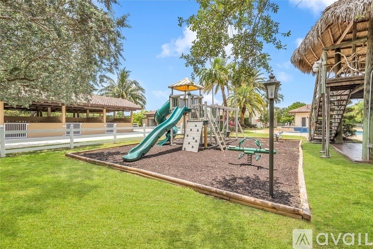 A playground with a green slide and a wooden swing set.