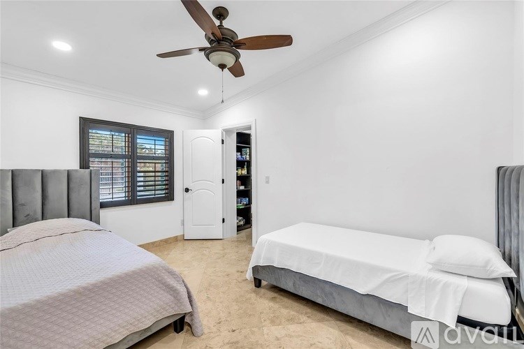 A bedroom with a bed, a ceiling fan, and a window with blinds.