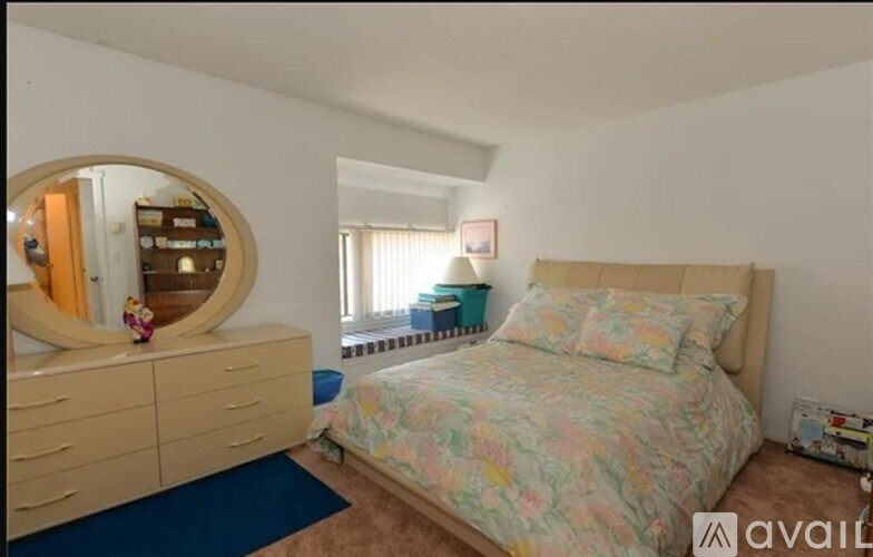 A bedroom with a floral bedspread and a round mirror on the dresser.