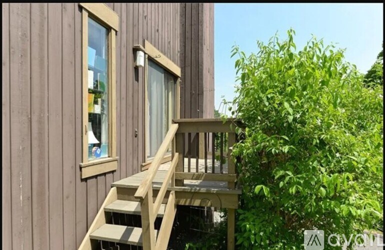 A wooden deck with a staircase leading to a window on a house.
