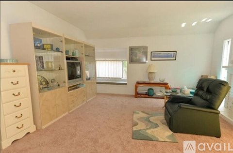 A living room with a black leather chair and a wooden cabinet.