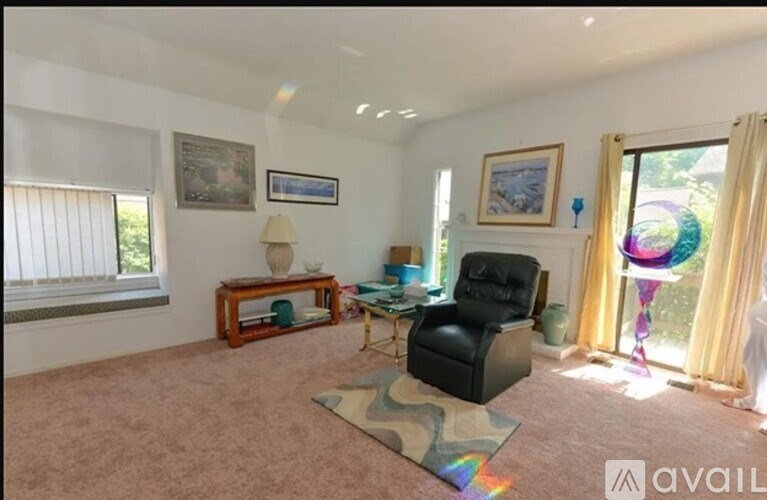 A living room with a black chair and a table with a lamp on it.