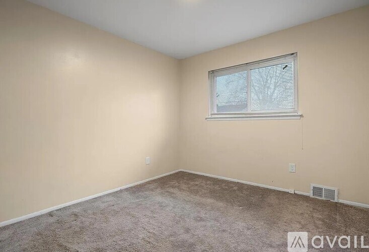 A room with a carpeted floor and a window with blinds.