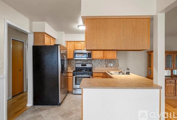 A kitchen with a black refrigerator and wooden cabinets.
