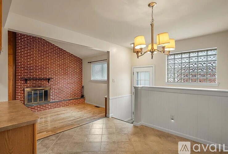 A room with a brick fireplace and a chandelier.