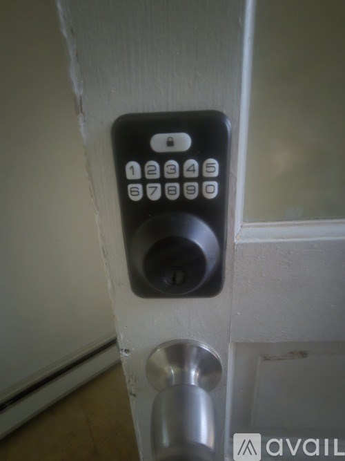 A black keypad with numbers 1 to 9 and a key 0 is mounted on a white door.