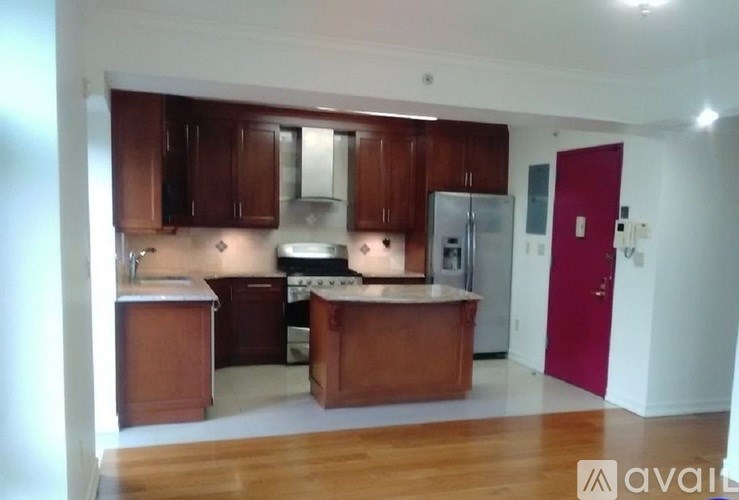 A kitchen with wooden cabinets and a red door.