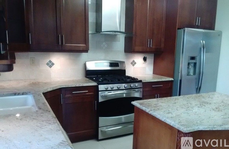 A kitchen with dark wood cabinets and a granite countertop.