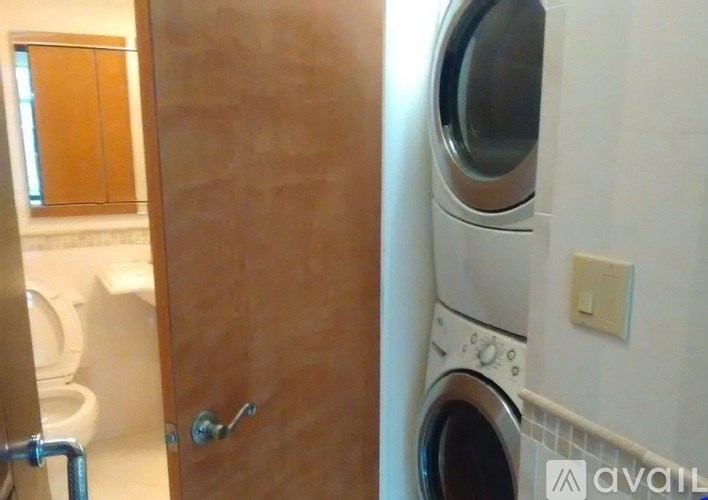 A washing machine is in a bathroom next to a toilet.
