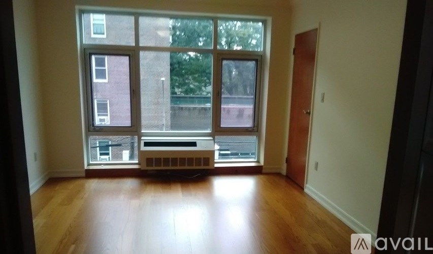 A room with wooden floors and a large window overlooking a building.