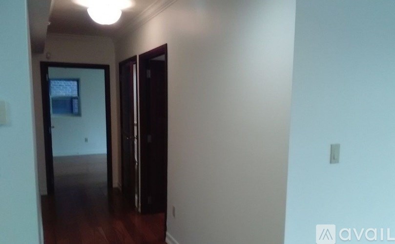 A hallway with a door on the right and a mirror on the wall.