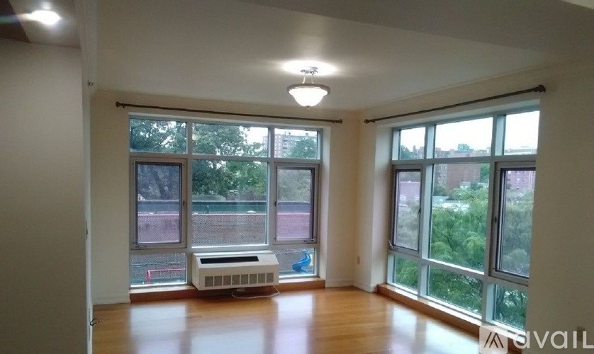 A room with a window overlooking a street with a bench in front of it.