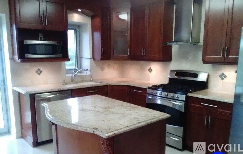 A kitchen with brown cabinets and a marble countertop.