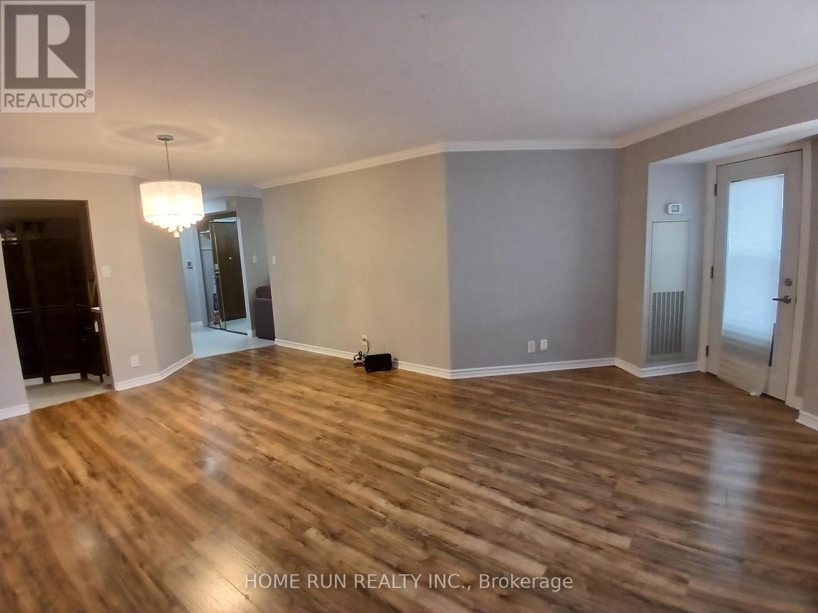 A room with wooden flooring and a chandelier hanging from the ceiling.