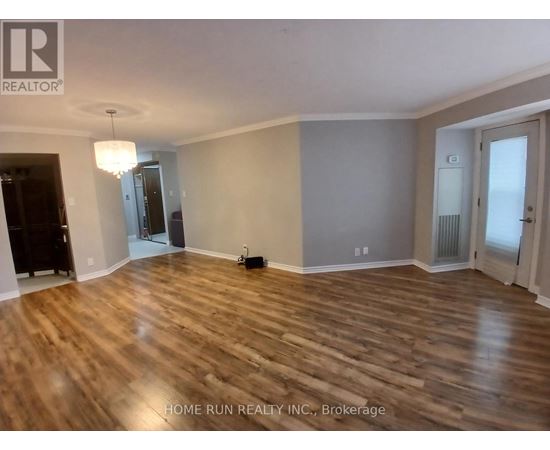 A room with wooden flooring and a chandelier hanging from the ceiling.