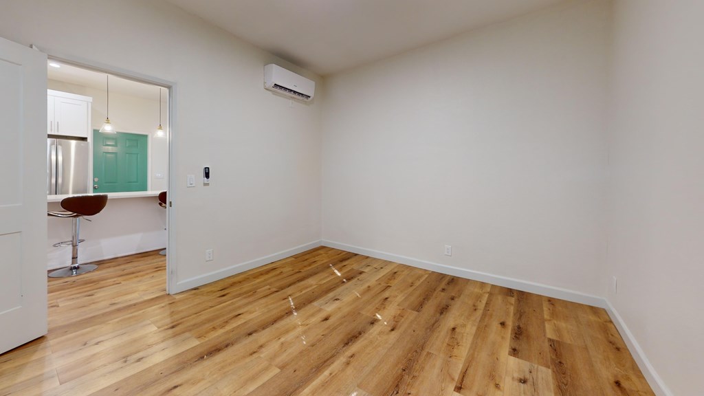 A room with wooden flooring and a mirror on the wall.